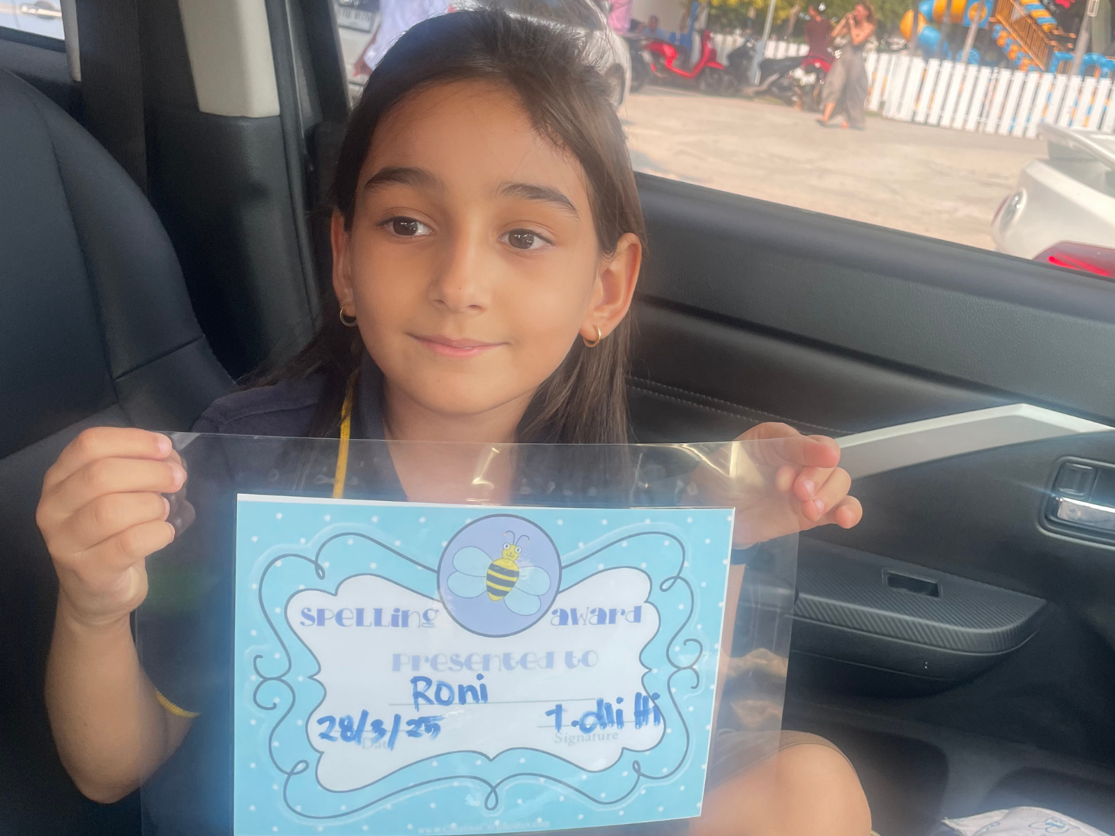 Roni holding the spelling certificate she earned after a month of practice